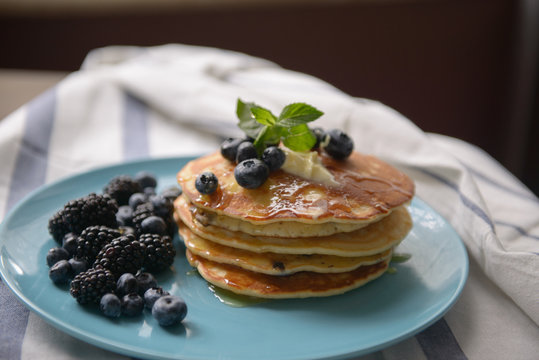 Pancakes with blackberries and blueberries on a blue plate