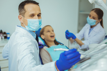 Need it. Charming assistant wearing face mask while helping her practitioner