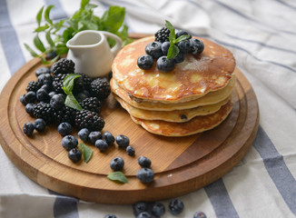 Pancakes with blackberries, blueberries and mint on the kitchen board - top view