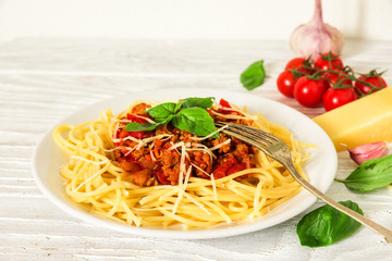 Spaghetti bolognese on a white plate with fork on white wooden table. healthy food