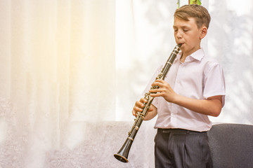 The boy learns to play the clarinet at the window. Musicology, music education and education.