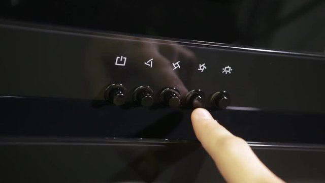 The man presses the buttons on the control panel with a modern extractor, ventilation