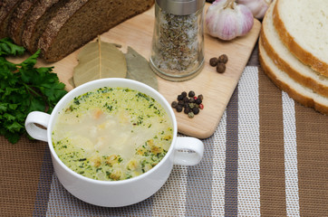 Mushroom soup with croutons in a white dish is on a wooden table.