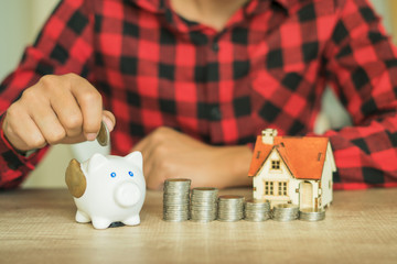 Male hand putting money coins with home, Saving for buy home concept