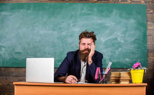 Educators More Stressed Work Than Average People. High Level Fatigue. Exhausting Work In School Causes Fatigue. Educator Bearded Man Sleepy Face Tired Sit Table Classroom. Life Of Teacher Exhausting