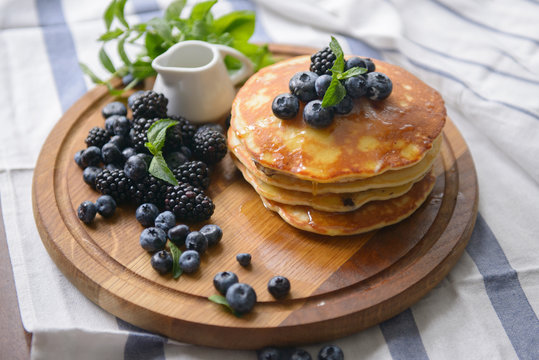 Pancakes and berries on the board with honey - top view