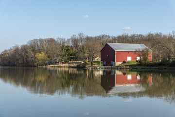 Fototapeta na wymiar Red barn on the lake shore with reflection