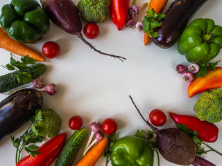 Fresh vegetables on a white background. Eggplant, beets, peppers, carrots, broccoli, cucumber, garlic, tomatoes.