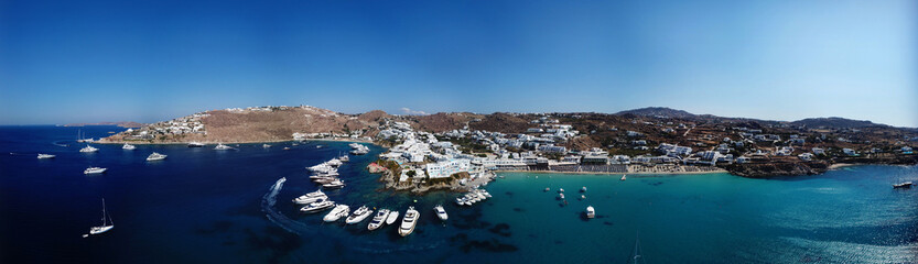 Fototapeta na wymiar Aerial ultra wide panoramic drone view of iconic turquoise clear water beach of Psarou and Platy Yalos with yachts docked, Mykonos island, Cyclades, Aegean, Greece