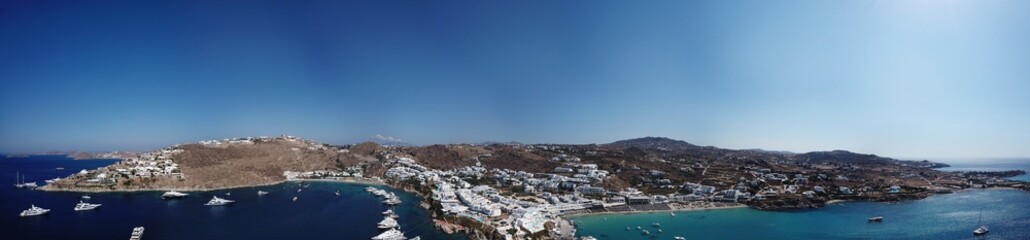 Aerial ultra wide panoramic drone view of iconic turquoise clear water beach of Psarou and Platy Yalos with yachts docked, Mykonos island, Cyclades, Aegean, Greece