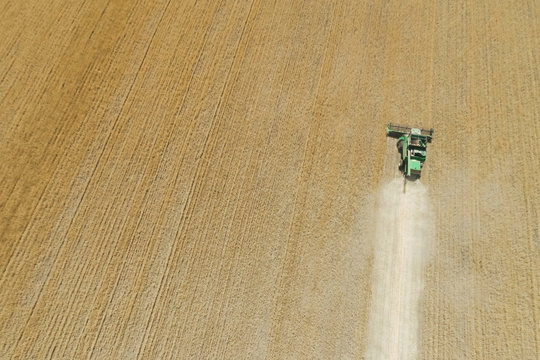 Modern combine harvester working on the wheat crop. Aerial view.