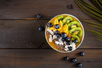 Peach smoothie bowl with kiwi fruit, chia seeds and coconut chips. Food photography with copy space.