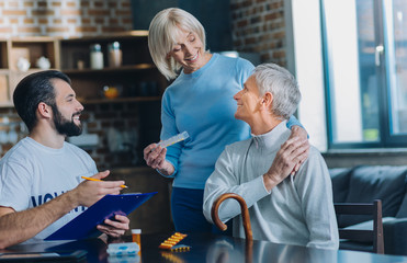 My dear wife. Cheerful old man smiling and looking at his wife standing behind him