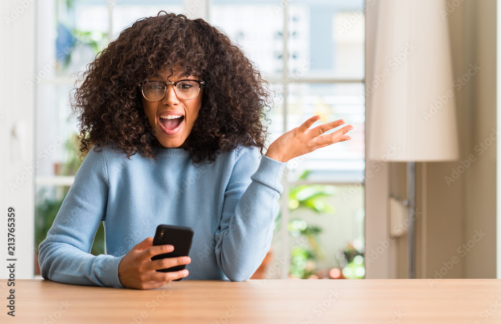 Sticker Beautiful african american woman using smartphone very happy and excited, winner expression celebrating victory screaming with big smile and raised hands