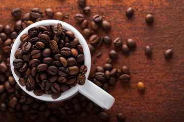  Photo closeup of coffee beans in white cup. Rusty background. Copy space.