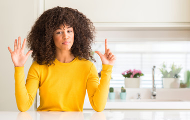 African american woman wearing yellow sweater at kitchen showing and pointing up with fingers...