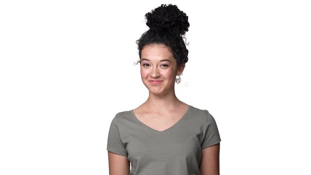 Portrait of content shy woman wearing basic t-shirt nodding and accept proposal with smile, isolated over white background in studio slow motion. Concept of emotions