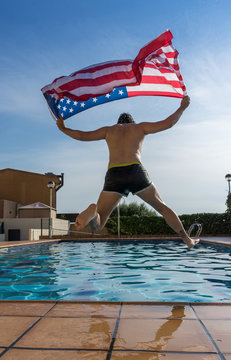 Man on vacation jumping to the pool with United states flag