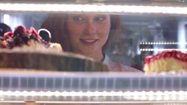 Woman choosing cake at cafe