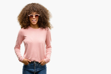African american woman wearing pink sunglasses winking looking at the camera with sexy expression,...