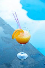 Glass of refreshing cocktail near the swimming pool