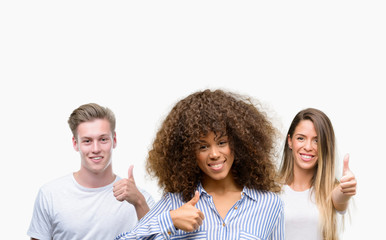 Group of young people over white background happy with big smile doing ok sign, thumb up with fingers, excellent sign