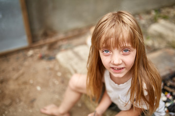 Portrait of tense vulnerable little girl in dirty alley, shallow depth of field.