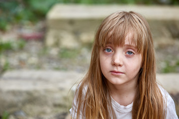Portrait of sad vulnerable little girl in dirty alley, shallow depth of field.