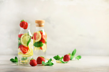 Fototapeta na wymiar Citrus and strawberry lemonade with mint, lemon on grey background. Detox drink. Summer fruit infused water. Copy space.
