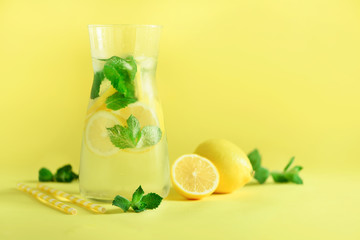 Fresh summer fruits water or lemonade with mint, ice, lemon on yellow background. Copy space. Summer infused water. Citrus flavored beverage.