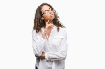 Beautiful young hispanic woman with hand on chin thinking about question, pensive expression....