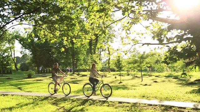 Young loving couple dating while riding bicycles in the park