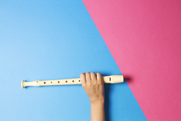 Kid hand with flute on colorful background © vejaa