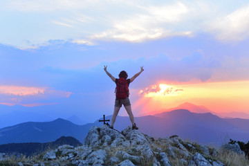 Woman who hiker reaches the top at sunset