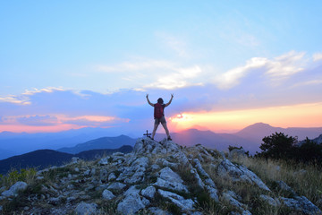 Woman who hiker reaches the top at sunset
