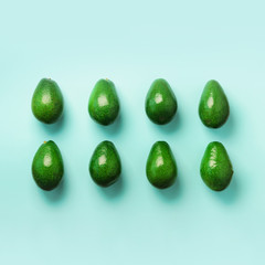 Green avocado pattern on blue background. Top view. Pop art design, creative summer food concept. Organic avocadoes in minimal flat lay style.