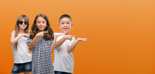 Group of boy and girls kids over orange background very happy pointing with hand and finger © Krakenimages.com