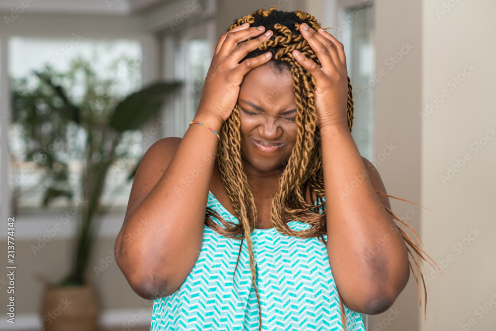 Sticker African american woman at home suffering from headache desperate and stressed because pain and migraine. Hands on head.