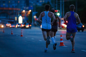 Group of sportsmen running on night road. Healthy lifestyle abstract background