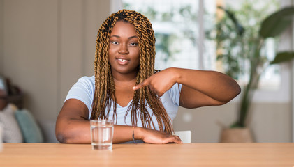 African american woman drinking water with surprise face pointing finger to himself