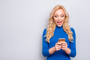 Portrait with copy space, empty place of pretty, trendy, charming, nice, sexy, cute, cheerful, woman with open mouth having smart phone in hands looking at screen with wondered, surprised expression