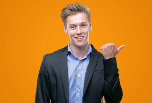 Young handsome blond business man pointing with hand and finger up with happy face smiling