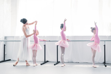 side view of ballet teacher exercising with children in ballet school