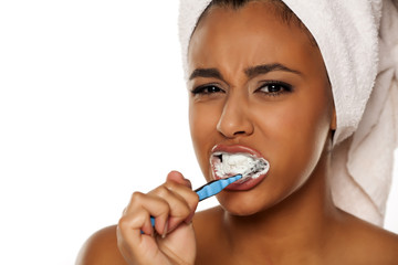 portrait of a young dark-skinned woman brushing her teeth on a white background