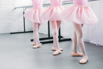 low section of cute little kids in pink tutu skirts and ballet shoes dancing in studio - Powered by Adobe