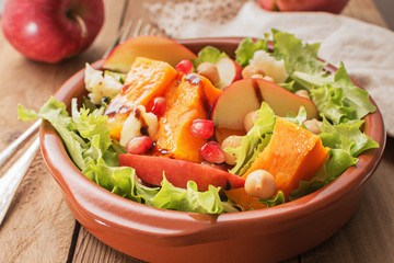 Fall salad with apple ,pumpkin and melogran on rustik background.