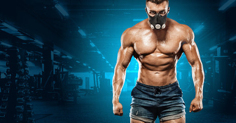 Fototapeta na wymiar Brutal strong muscular bodybuilder athletic man pumping up muscles on gym background. Workout bodybuilding concept. Copy space for sport nutrition ads.