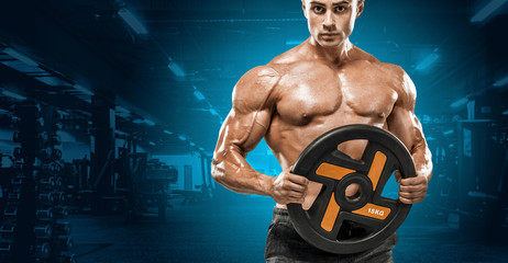 Brutal strong muscular bodybuilder athletic man pumping up muscles workout bodybuilding concept background - handsome men doing exercises in gym naked torso. Copy space for sport nutrition ads.