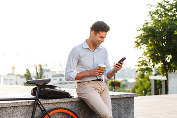 Obraz premium Smiling young stylish man using mobile phone