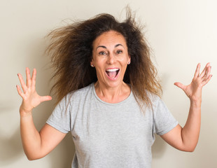 Curled hair brazilian woman very happy and excited, winner expression celebrating victory screaming with big smile and raised hands